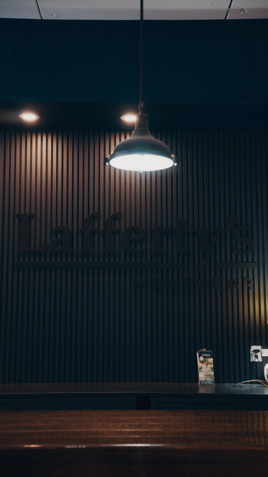 Lafferty's Menswear wordmark on the slatted wood feature wall above the counter